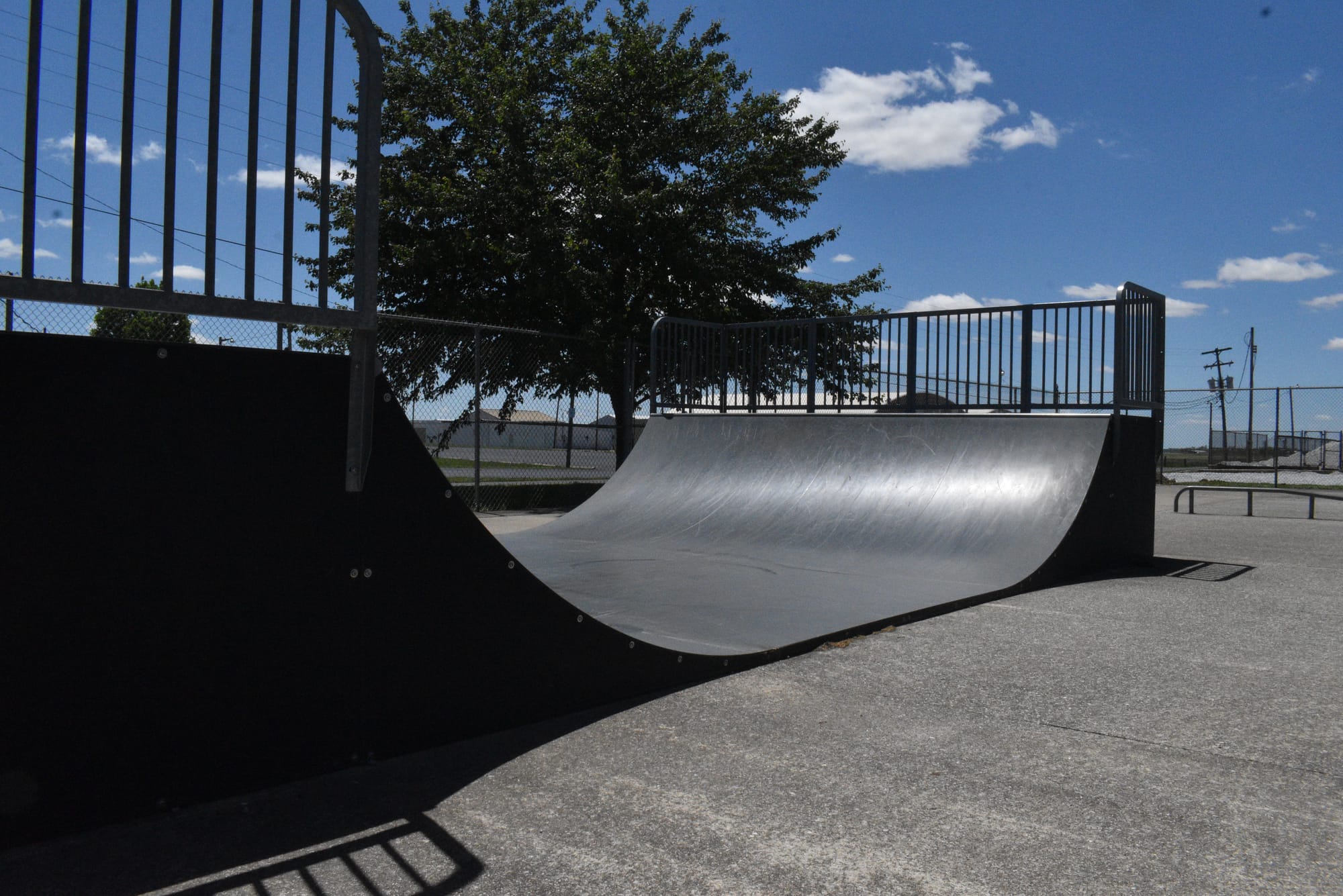 A photo of a small half pipe ramp at the Decatur County Skate Park. The ramp is black and approximately 4 feet high with metal rails at the top. Photo by Noelle Maxwell.