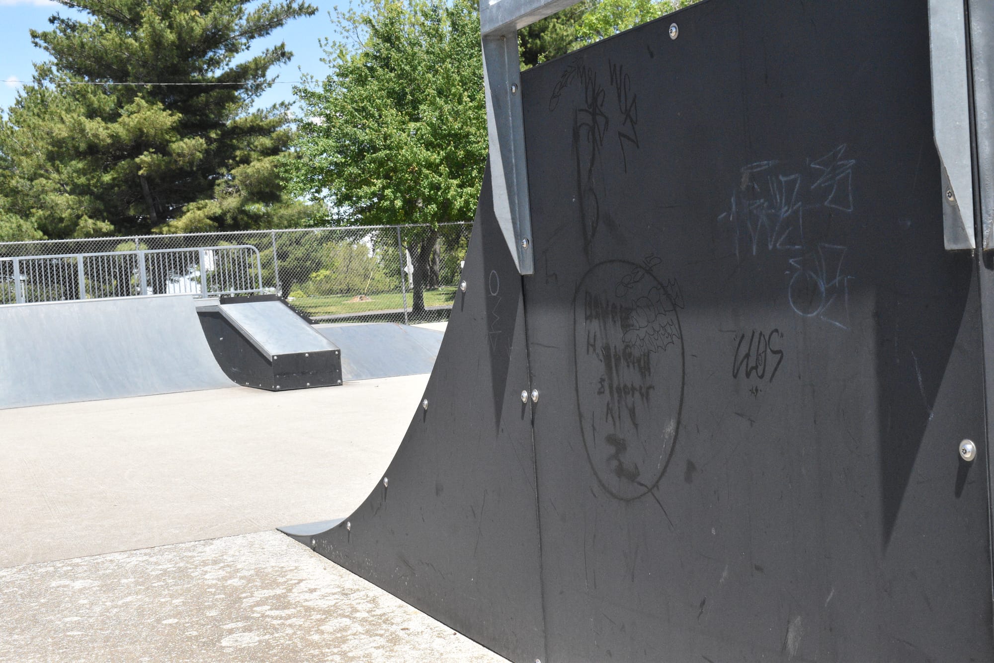 Illegible graffiti in black ink/paint and white ink/paint on the side of a black quarter pipe ramp at the Decatur County Skate Park. Photo by Noelle Maxwell.