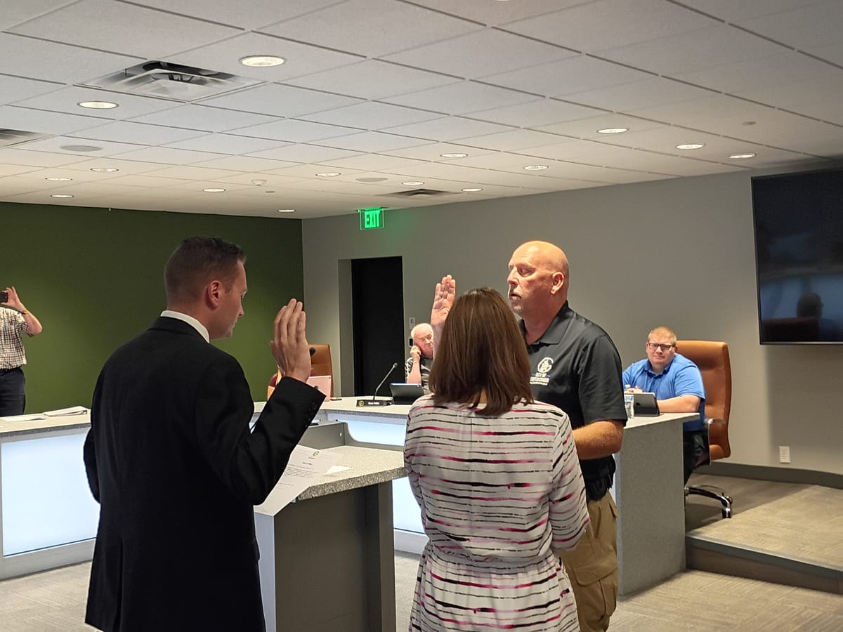 Greensburg Elementary School Resource Officer Kenneth Woodall, a bald white man wearing a black City of Greensburg polo shirt and tan cargo uniform pants, being sworn-in by Mayor Joshua Marsh