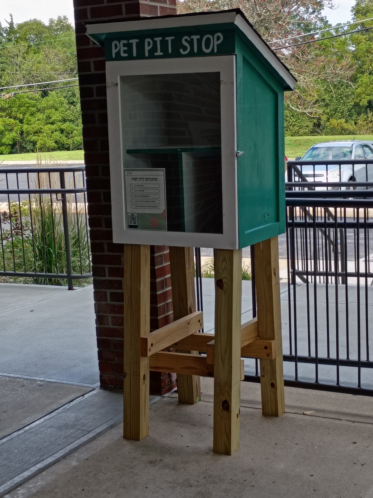 A "pet pit stop" box at the Greensburg-Decatur County Public Library. The box is painted green and has a glass front door with a flier in the front. Photo by Noelle Maxwell.